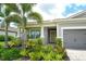 Inviting entryway with a decorative front door, side-entry garage access, and colorful landscaping at 8668 Sundance Loop, Sarasota, FL 34238