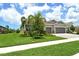 Beautiful home with a lush green lawn, mature trees, landscaping, and a paver driveway leading to the garage at 8668 Sundance Loop, Sarasota, FL 34238