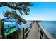 Waterfront view of a wooden dock extending to boat slips with clear blue water, and informative signage nearby at 8735 Midnight Pass Rd # 602B, Sarasota, FL 34242