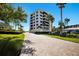 Elegant condo building featuring a private brick driveway, lush landscaping, and convenient parking at 8735 Midnight Pass Rd # 602B, Sarasota, FL 34242