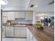 Bright kitchen featuring white cabinetry, tile flooring, and butcher block countertops with views to the living area at 8735 Midnight Pass Rd # 602B, Sarasota, FL 34242