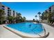 Community pool and lounge area surrounded by palms and lush vegetation at 8735 Midnight Pass Rd # 602B, Sarasota, FL 34242