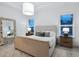 Bright bedroom with a neutral palette, large windows, and a decorative mirror at 10120 Carnoustie Pl, Bradenton, FL 34211