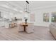Bright dining area with a wooden table, modern lighting, and an open view to the kitchen and outdoor pool at 10120 Carnoustie Pl, Bradenton, FL 34211