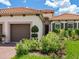 Elegant exterior view showcasing lush landscaping, a two-car garage, and a stylish terracotta-tiled roof at 10120 Carnoustie Pl, Bradenton, FL 34211