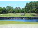 Picturesque golf course featuring a water hazard, lush green fairway, and golf cart, on a sunny day at 10120 Carnoustie Pl, Bradenton, FL 34211