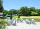 Outdoor patio featuring tables and chairs surrounded by mature trees and a manicured lawn at 10120 Carnoustie Pl, Bradenton, FL 34211