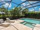 Screened-in pool area with a swimming pool, spa, lounge chairs, stone patio, and manicured greenery at 10120 Carnoustie Pl, Bradenton, FL 34211