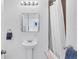 Bright bathroom featuring a pedestal sink, mirrored cabinet, and a shower with a white curtain at 1168 Westway Dr, Sarasota, FL 34236