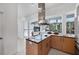 Modern kitchen featuring a stainless steel range hood, cooktop, natural wood cabinetry, and expansive windows at 1168 Westway Dr, Sarasota, FL 34236