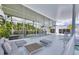 Covered patio featuring modern white furniture, large glass windows, and a view of the lush backyard with a swimming pool at 1168 Westway Dr, Sarasota, FL 34236