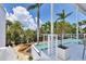 Swimming pool next to a patio area with a white railing, surrounded by lush vegetation and tropical plants at 1168 Westway Dr, Sarasota, FL 34236