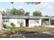 Street view of single-story home featuring a light exterior, carport, tidy landscaping, and mature trees at 1207 65Th Nw St, Bradenton, FL 34209