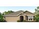 Charming single-story home featuring a two-car garage, tan siding and a beautifully landscaped front yard at 12071 Mountain Island Trl, Parrish, FL 34219