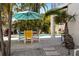 Outdoor patio area featuring an umbrella-covered dining table near lush tropical landscaping and the pool at 123 52Nd St # B, Bradenton Beach, FL 34217