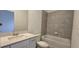 Bright bathroom with a single sink vanity, tiled bathtub/shower, and neutral color scheme at 15127 Oxford Grey Dr, Bradenton, FL 34211