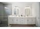 Bright bathroom featuring double vanity with modern hardware, mirrors, and elegant lighting at 17737 Savory Mist Cir, Bradenton, FL 34211