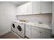 Well-equipped laundry room with modern washer, dryer, sink, and ample cabinet space at 17737 Savory Mist Cir, Bradenton, FL 34211