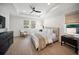 Large primary bedroom with hardwood floors, tray ceiling, fan, and modern design at 17737 Savory Mist Cir, Bradenton, FL 34211