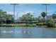 Picturesque view of tennis courts beside a serene pond with mature trees on a sunny day at 2217 Muesel St, Sarasota, FL 34237