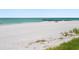 Picturesque beach with white sand, clear turquoise water, and a wooden pier at 2295 Gulf Of Mexico Dr # 64S, Longboat Key, FL 34228
