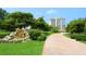 Well-manicured landscaping around the building with a small water feature to the left of the paved drive at 2295 Gulf Of Mexico Dr # 64S, Longboat Key, FL 34228
