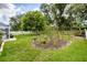 Well-maintained backyard featuring lush green grass, mature trees, and a charming flower bed adding natural beauty at 2381 Appaloosa Cir, Sarasota, FL 34240