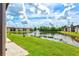 Scenic view of condo community pond featuring manicured lawn and mature trees under a sunny sky at 25100 Sandhill Blvd # 104 G, Punta Gorda, FL 33983