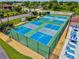 Aerial view of tennis courts with a seating area surrounded by a fence and landscaping at 25100 Sandhill Blvd # 104 G, Punta Gorda, FL 33983