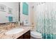 Well-lit bathroom with a granite countertop, decorative mirror, and shower-tub combination with stylish curtain at 25324 Alicante Dr, Punta Gorda, FL 33955