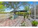 Outdoor kitchen featuring a built-in grill, red brick floor, and lush landscaping at 25324 Alicante Dr, Punta Gorda, FL 33955