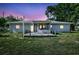 Back of a single-story home featuring a wooden deck and a covered porch under a colorful sunset sky at 2622 11Th W Ave, Bradenton, FL 34205