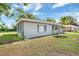 Rear-side view of a single-story home with a covered porch, a lush lawn and mature trees under a bright sky at 2622 11Th W Ave, Bradenton, FL 34205