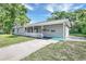 Side view of a single-story home with a covered porch, a lush lawn and mature trees under a bright sky at 2622 11Th W Ave, Bradenton, FL 34205