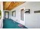 Covered front porch with a wooden ceiling, front door, mailbox, and a welcome mat, creating a cozy entry at 2622 11Th W Ave, Bradenton, FL 34205
