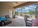 Spacious screened-in patio features brick flooring, ceiling fan, outdoor furniture, string lights, and access door at 3041 Stonegate Falls Dr, Land O Lakes, FL 34638