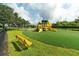 Bright yellow community playground featuring multiple slides and climbing structures on a lush green lawn at 362 Fairway Isles Ln, Bradenton, FL 34212