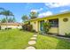 Charming one-story home featuring a well-manicured lawn, stepping stones to front door and a bright yellow exterior at 409 Archibald Ave, Sarasota, FL 34243