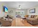 Bright living room with wood floors, a ceiling fan, and sliding glass doors to the screened-in porch at 409 Archibald Ave, Sarasota, FL 34243