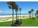 Lush landscaped lawn leading to a pristine beach with white sands, clear waters, and swaying palm trees at 4325 Gulf Of Mexico Dr # 204, Longboat Key, FL 34228