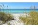 Scenic beach view framed by natural seagrass with turquoise water and clear blue skies at 4325 Gulf Of Mexico Dr # 204, Longboat Key, FL 34228