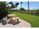Outdoor patio with beautiful stone table, lush green grass, and ocean view in the distance at 4325 Gulf Of Mexico Dr # 204, Longboat Key, FL 34228