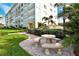 Exterior common area with outdoor dining furniture, manicured lawns, and palm trees at 4325 Gulf Of Mexico Dr # 204, Longboat Key, FL 34228