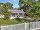 Charming home featuring a screened porch, white picket fence, and lush landscaping, creating a welcoming curb appeal at 520 27Th W St, Bradenton, FL 34205
