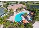 Aerial view of a community pool and clubhouse surrounded by lush tropical landscaping and ample seating at 5863 Cavano Dr, Sarasota, FL 34231