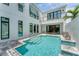 Modern white home featuring an outdoor private pool with waterfall feature, stylish patio, and large glass doors at 6028 Red Mangrove Ln, Bradenton, FL 34210
