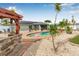 Backyard with a sparkling pool, rock waterfall feature, palm trees, and a barbecue area at 6178 Coliseum Blvd, Port Charlotte, FL 33981