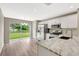 Modern kitchen with white cabinets, stainless steel appliances, stone countertops, and a view of the backyard at 6352 Robin Cv, Lakewood Ranch, FL 34202