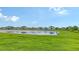 Lush green backyard featuring a serene pond, blending natural beauty with residential comfort at 6435 165Th E Dr, Parrish, FL 34219