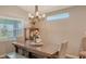 Dining table illuminated by a stylish chandelier sits next to a window, offering a bright and welcoming space at 6435 165Th E Dr, Parrish, FL 34219